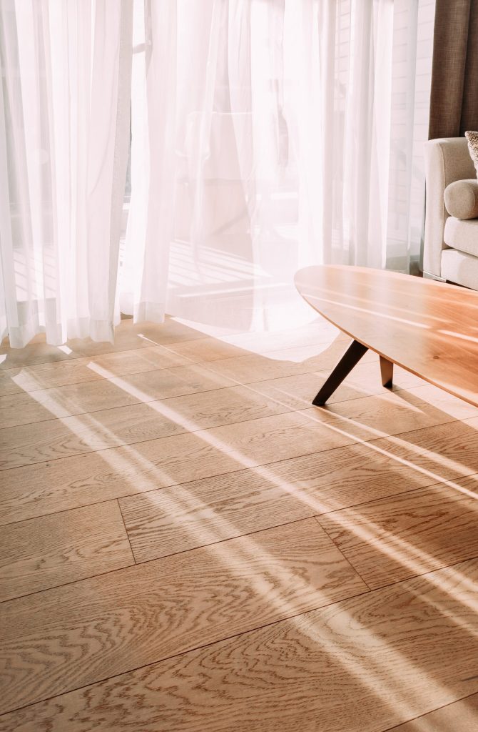 Modern room interior with an open window in minimal style. Transparent tulle with morning sun rays on shadow background. Vertical photo